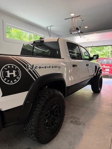 Modified white and black pickup truck with Hennessey branding displayed in an indoor showroom with bright lighting